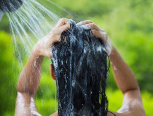 Frau wäscht sich ihre Haare im Freien